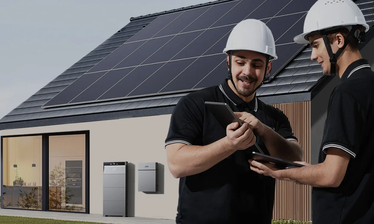 Twee installateurs bij een Anker SOLIX X1 aan een woning met zonnepanelen